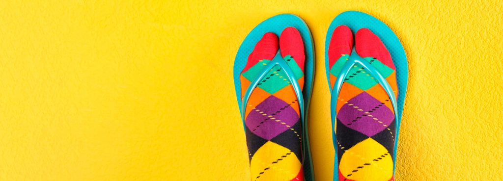 colourful bad taste socks and flip flops on yellow background