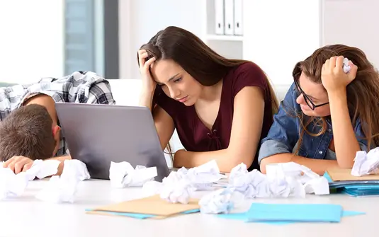 Three people struggling at a laptop