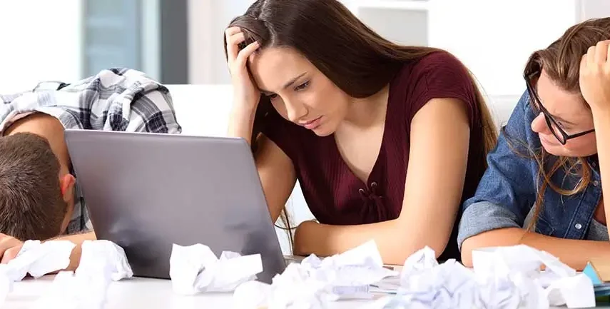 Three people struggling at a laptop